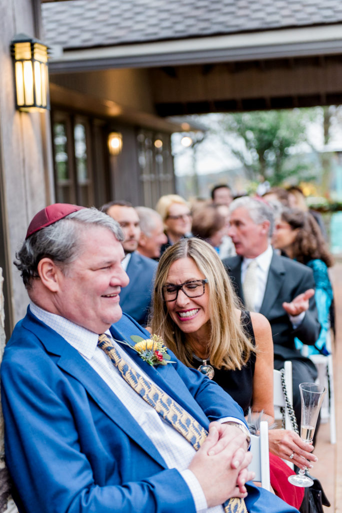 Candid moments shared between father of the bride and guest, photographed by New Jersey fine art hybrid photographer, Michelle Behre Photography, private estate fall wedding in at Lake Louise, Dallas, Pennsylvania.