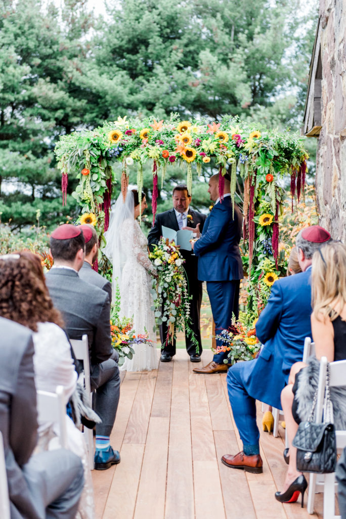 the bride hand in hand under the chuppah, photographed by New Jersey fine art hybrid photographer, Michelle Behre Photography, private estate fall wedding in at Lake Louise, Dallas, Pennsylvania.