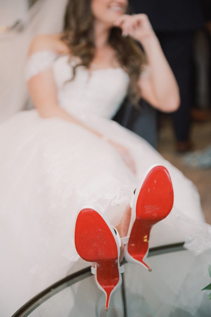 The bride relaxing in Christian Louboutin moments prior to her first dance at the RiverCrest Golf Club adorned in an elegant bridal gown and Christian Louboutin shoes by wedding photographers Michelle Behre Photography.